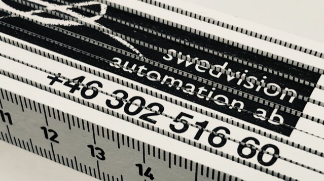 Närbild på en tumstock med Swedvisions logotyp på.